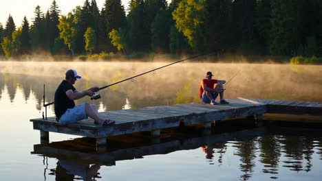 two men fishing at sunrise on a wooden pier