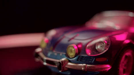 a close-up of a blue toy car illuminated by pink light