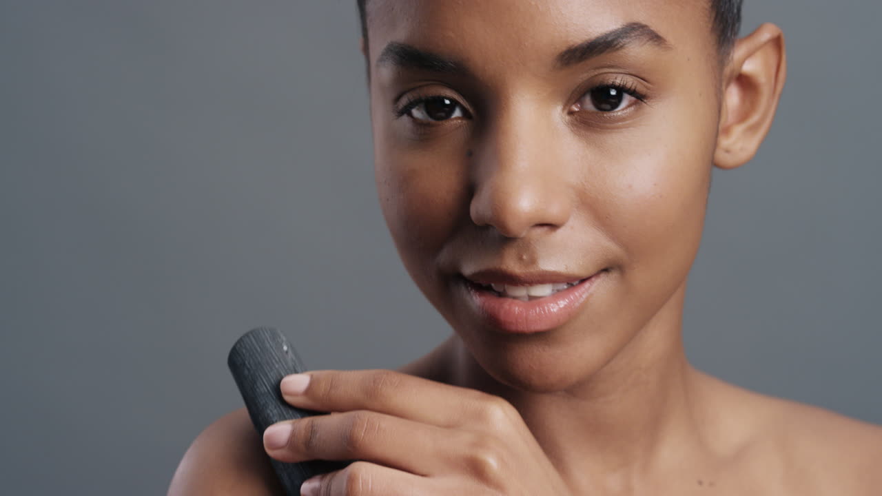 close up portrait gorgeous african american woman gently touching skin with charcoal caressing soft natural complexion enjoying sensual exfoliation beauty concept