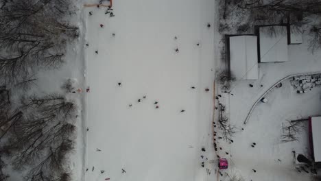 Skiers-and-snowboarders-skiing-on-snow-slopes-with-ski-lift-at-weekend.-Drone-flying-over-snowy-Slope-with-Skiers-and-Snowboarders-at-Ski-Resort-on-a-frosty-winter-day:-drone-view