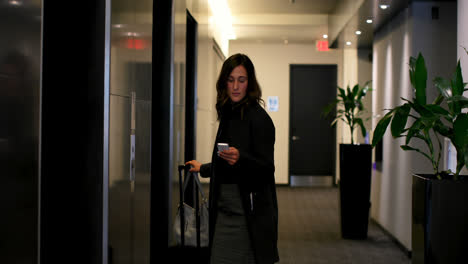 Beautiful-caucasian-businesswoman-using-mobile-phone-near-elevator-in-a-hotel-4k