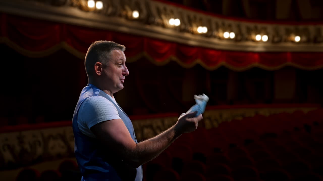 Man takes of protective mask from face and ready to perform from the stage. Rich interior of classic theater. End of lockdown.