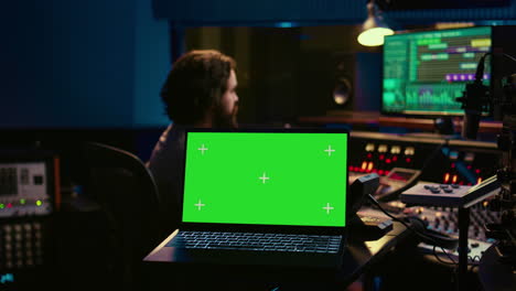 Sound-designer-uses-audio-mixer-and-greenscreen-layout-in-professional-studio