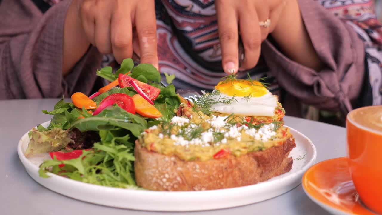 mujer disfrutando de un delicioso desayuno de tostadas de aguacate con huevo, ensalada y café