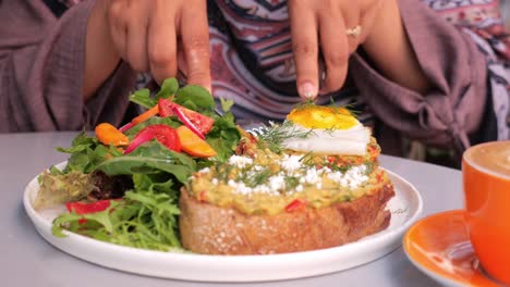 mujer disfrutando de un delicioso desayuno de tostadas de aguacate con huevo, ensalada y café