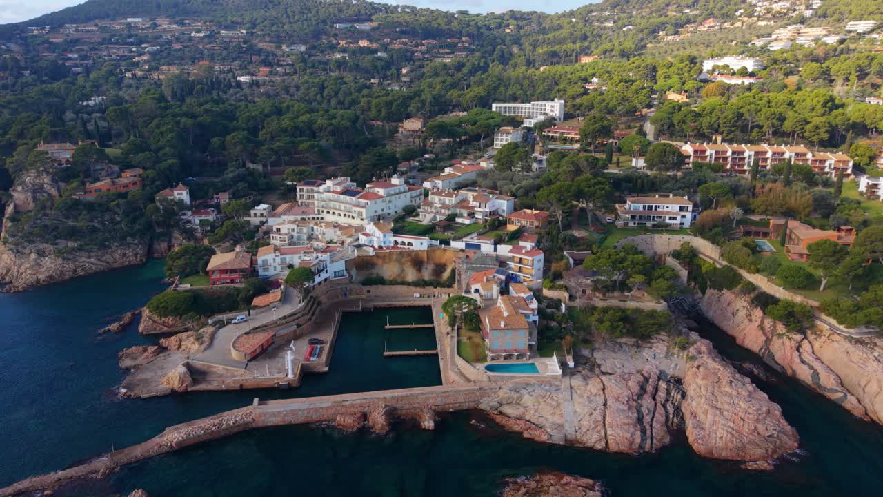 Spektakulært luftfoto af den charmerende kystby Fornells de Mar i Girona, der viser dens maleriske havn, robuste klipper og traditionelle hvide huse på en solskinsdag