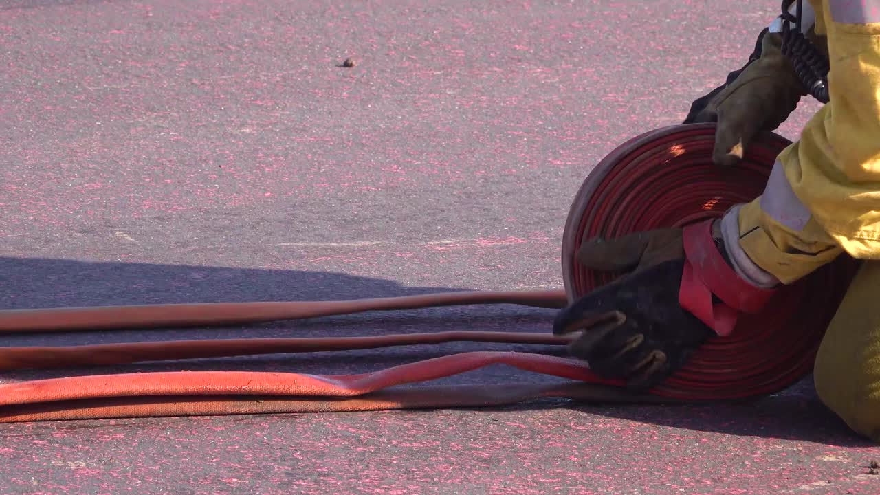 소방관은 남부 캘리포니아의 언덕에서 쉬운 산불을 따라 호스를 감습니다.