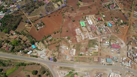 Aerial-of-a-town-and-sunlit-fields,-golden-hour-in-rural-Africa---tracking,-drone-shot