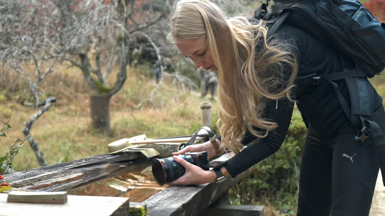 A serene stock video of a girl filming by a tranquil fountain along the Nakasendo Trail in Japan.