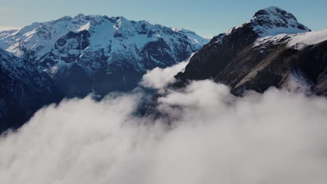 drone video flying through the clouds towards a snowy mountain range