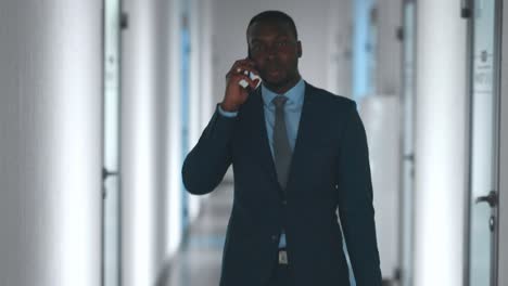 businessman talking on phone in office corridor