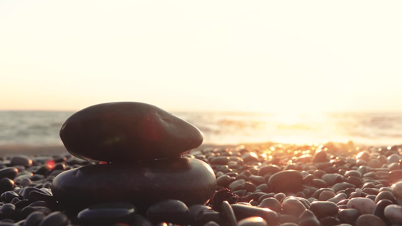 해가 뜨는 해변에 있는 젠 돌들