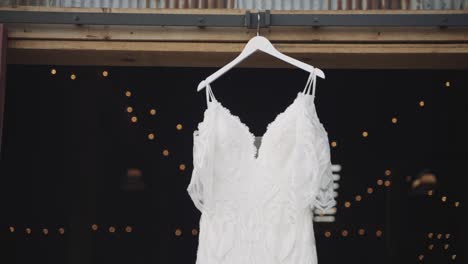 handheld, beautiful white wedding dress hanging from a barn door