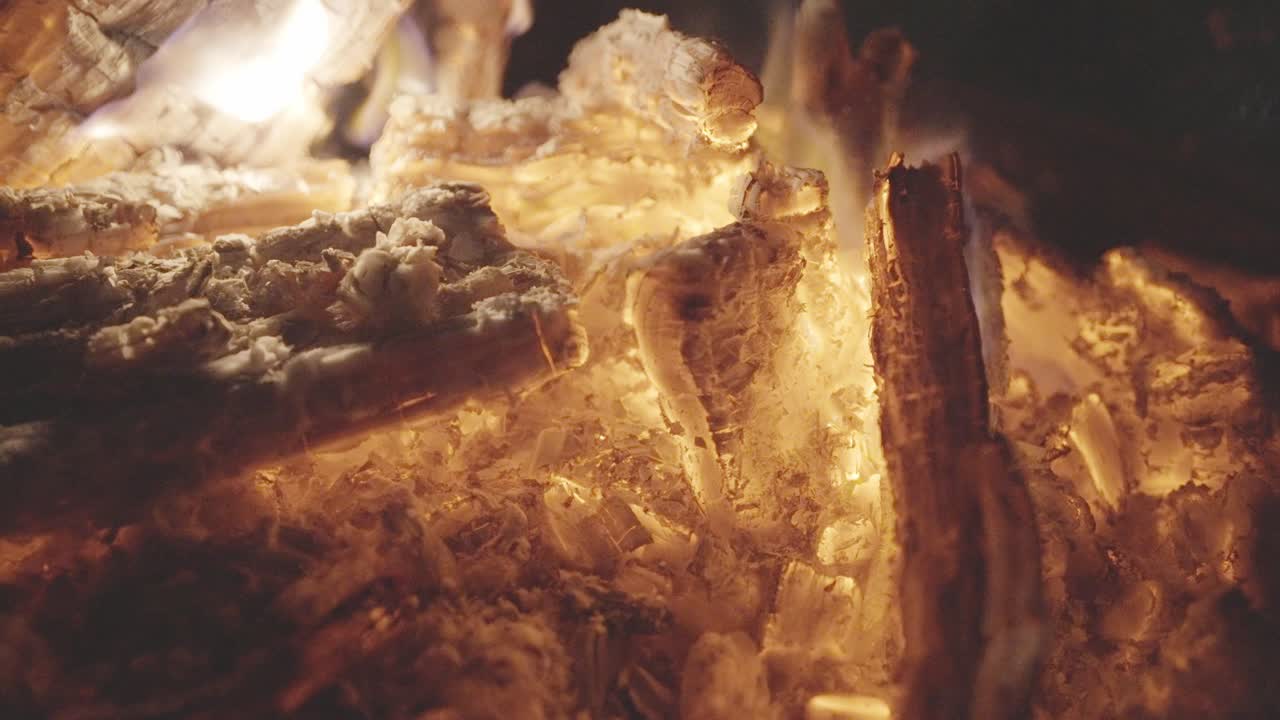 Glowing firewood burning, hot flames, crackling ember fuel, close-up
