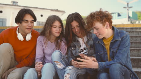 Un-Grupo-De-Adolescentes-Con-Dos-Chicas-Y-Dos-Chicos-Viendo-Algo-Divertido-En-Un-Teléfono-Celular-1