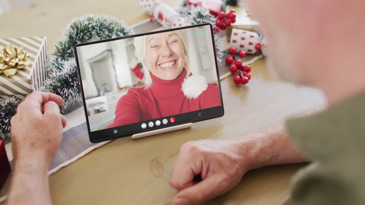 hombre caucásico con decoraciones de navidad teniendo llamada de video de tableta con mujer caucásica