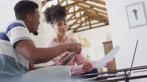una feliz pareja afroamericana usando una computadora portátil juntos en la sala de estar
