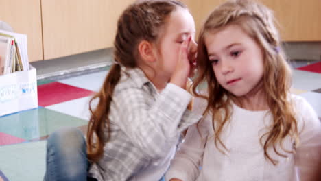 dos alumnas de primaria susurrando en la clase