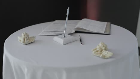 magnífica y limpia mesa de firma de bodas establecida con adornos blancos de querubines ángeles y una elegante pluma blanca en el siguiente restaurante en stittsville, ontario