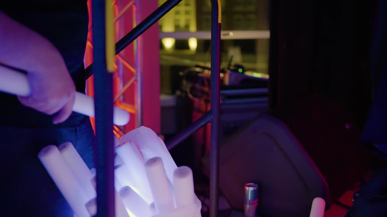 Hands putting used glow sticks inside bag during event, backstage. Gimbal, close up