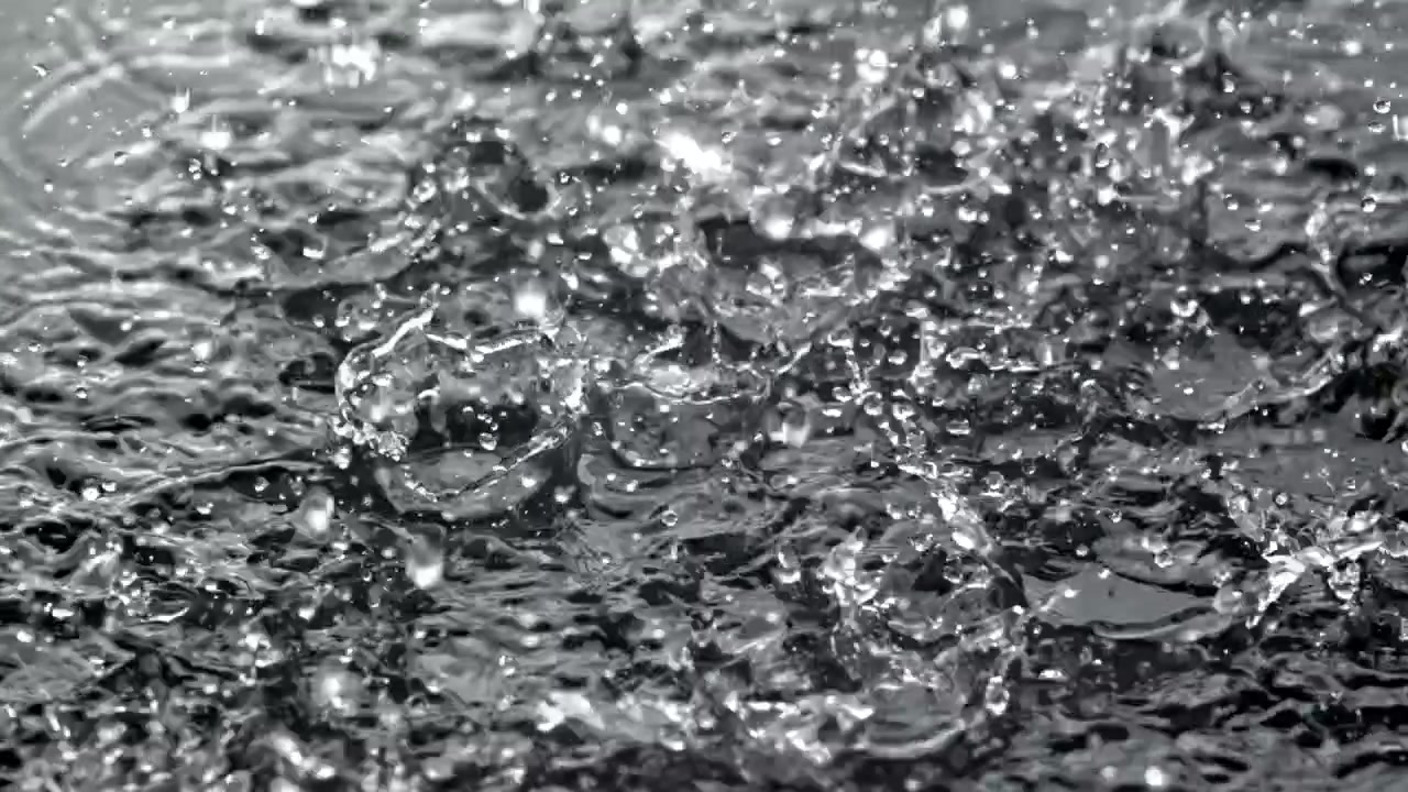 Regentropfen spritzen in Zeitlupe auf Wasseroberfläche