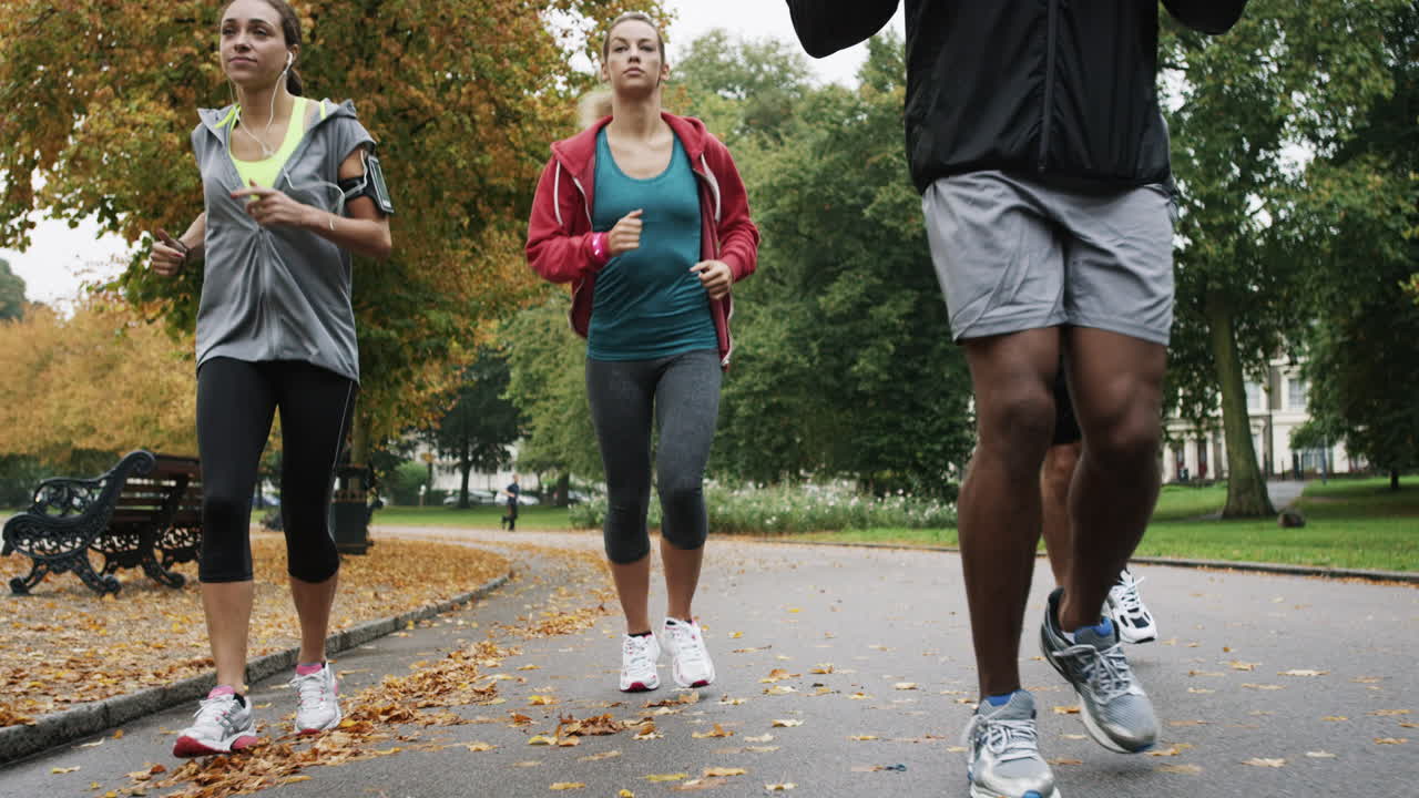 Group of runners running in park wearing wearable technology connected devices