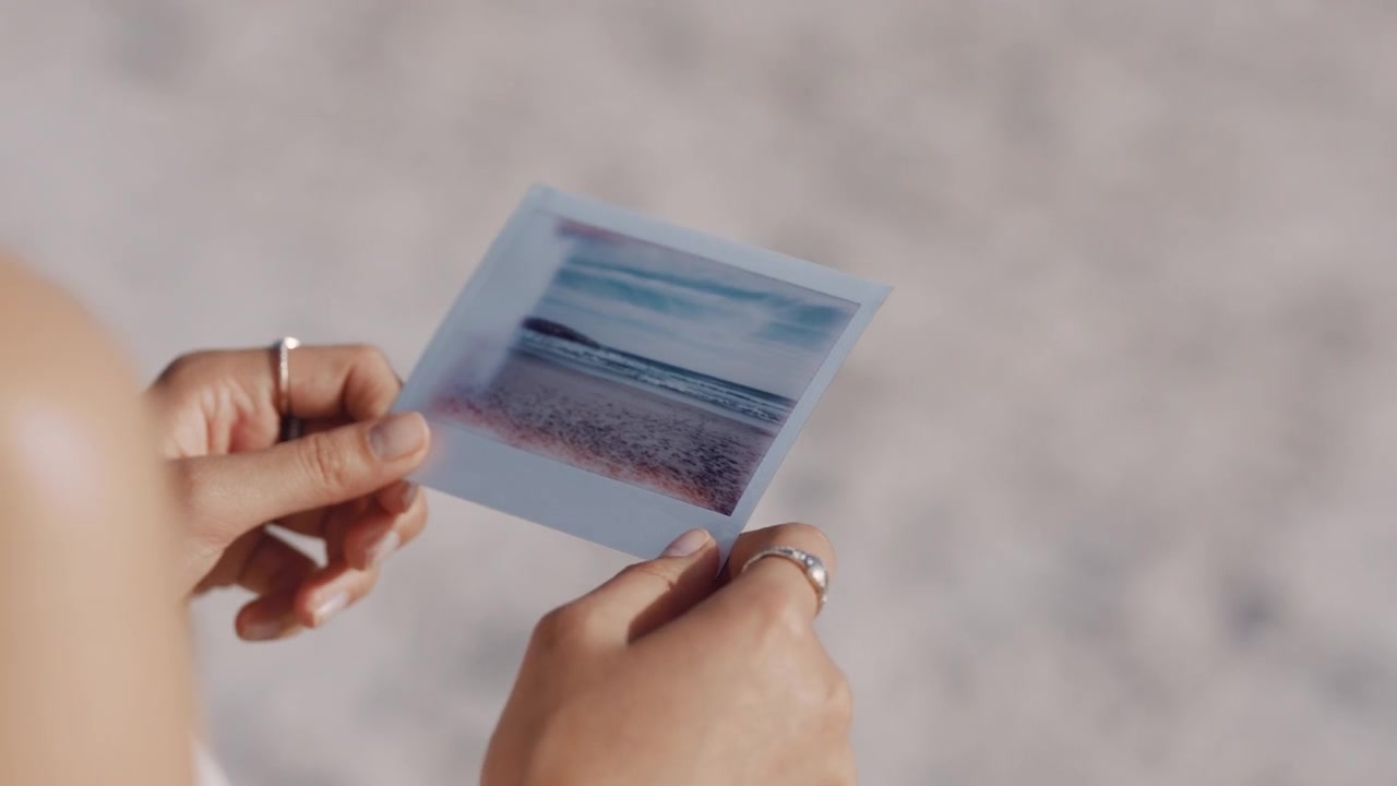 da vicino con la mano una fotografia di un bellissimo turista sulla spiaggia che si gode l'esperienza di fotografare una vacanza