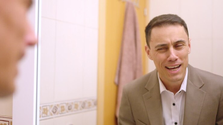 Businessman dressing up and checking himself in bathroom mirror