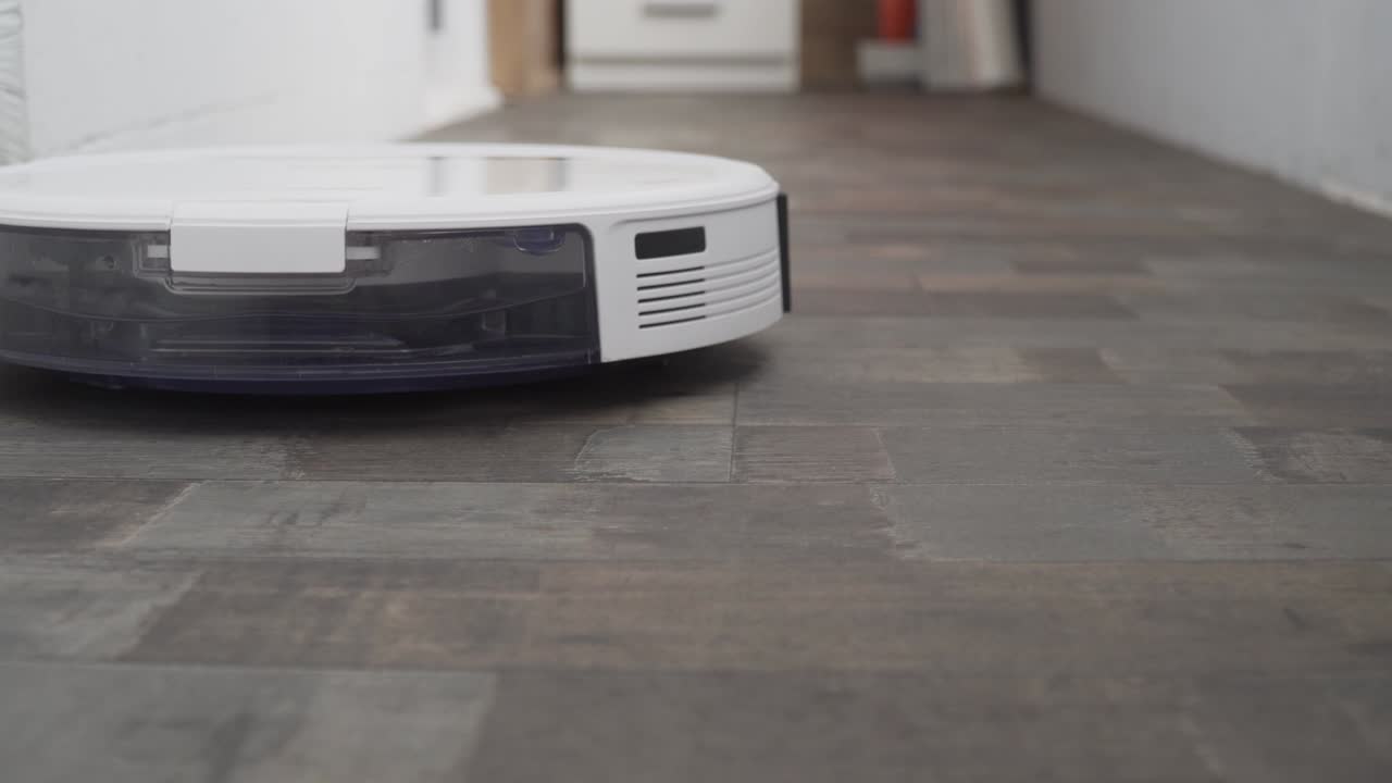 el robot aspirador automático se mueve a lo largo de su trayectoria. robot aspirador limpieza automática en el hogar. casa inteligente. moderno aspirador robótico limpia el piso. toma de primer plano. tecnologías modernas