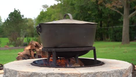 an old fashioned iron kettle over the fire of an outdoor campfire