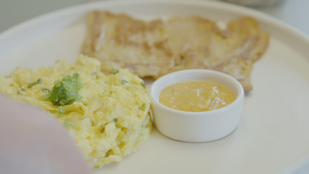 Close-up of a traditional dish that combines juicy roast meat, mote pillo prepared with mote, egg and finely chopped scallions, accompanied by artisanal chili sauce