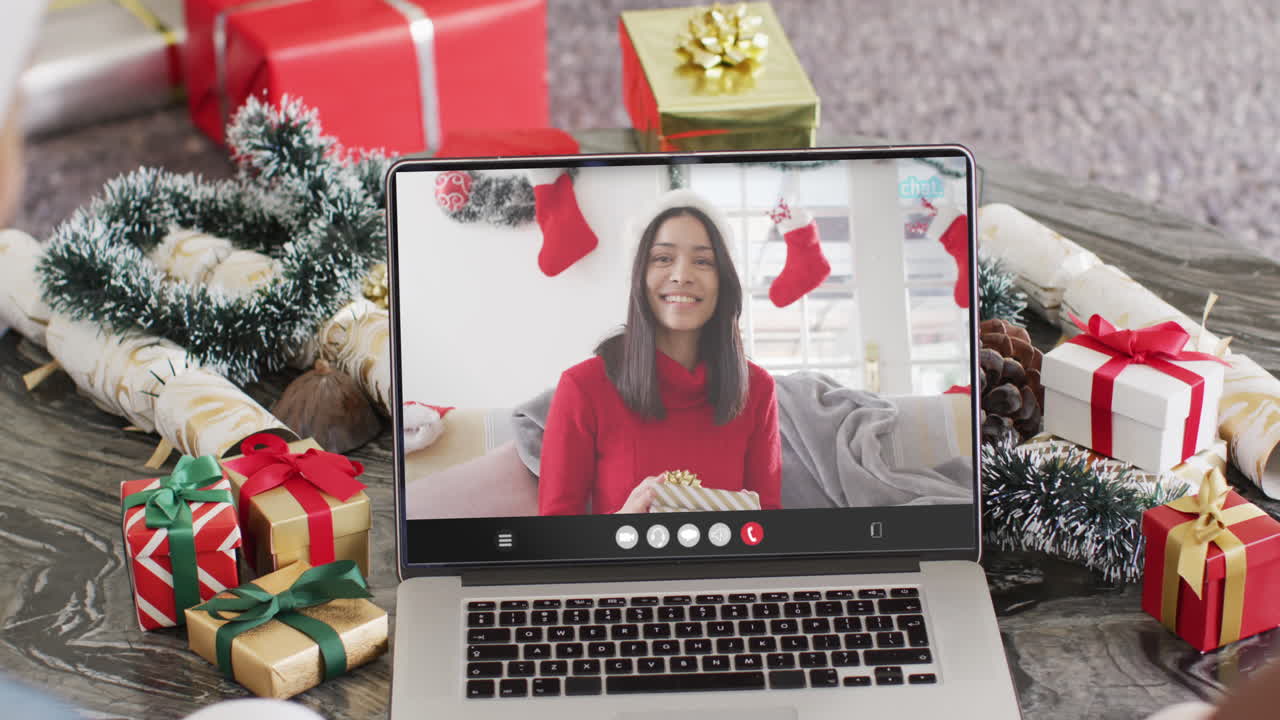pareja diversa con sombreros de santa teniendo llamada de video portátil con mujer biracial