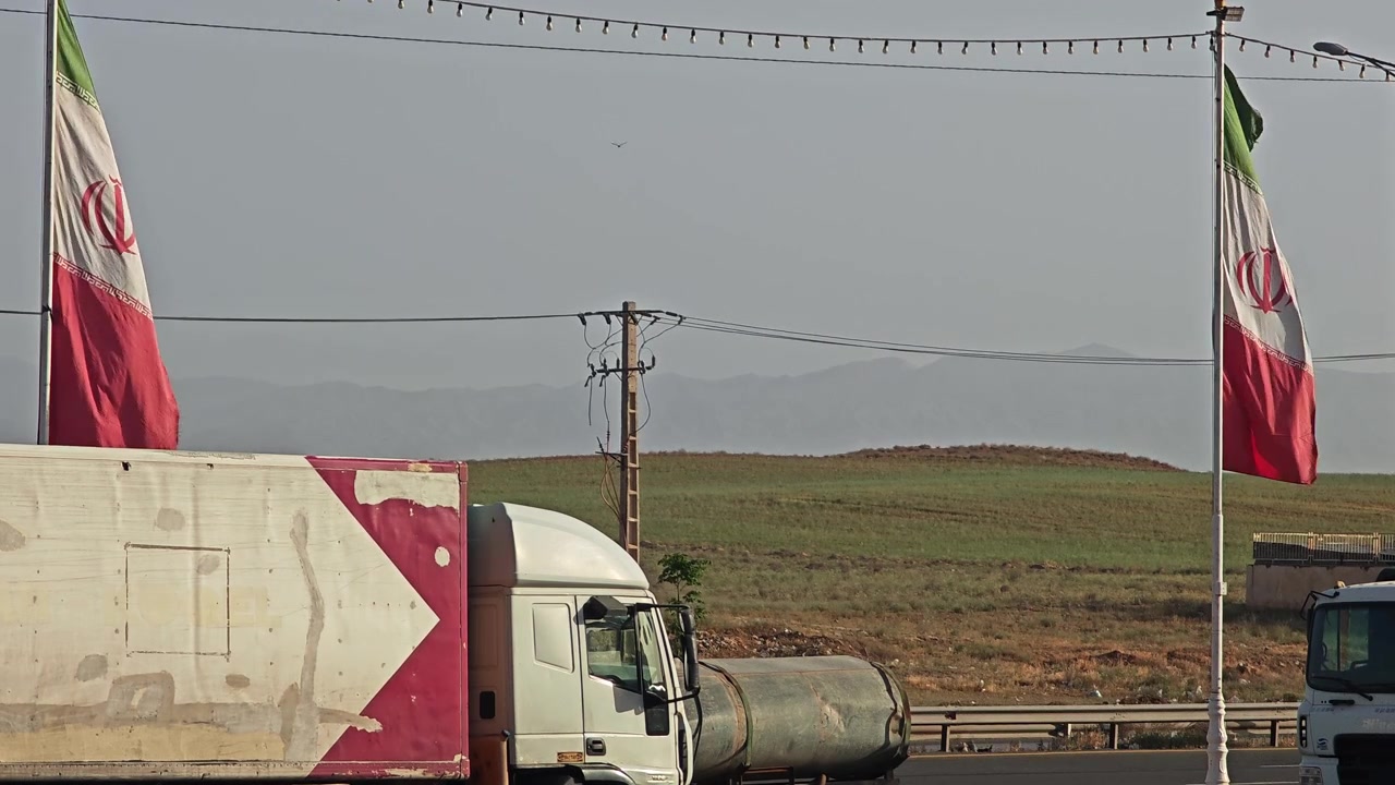 Iranian Flags Waving on Highway with Passing Traffic