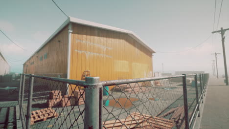 rusty warehouse with pallets and chain link fence