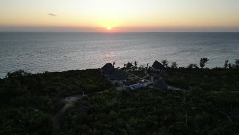 kisini beach bungalow resort con puesta de sol en el océano en el este de la isla de zanzíbar tanzania áfrica, tiro de aproximación aérea