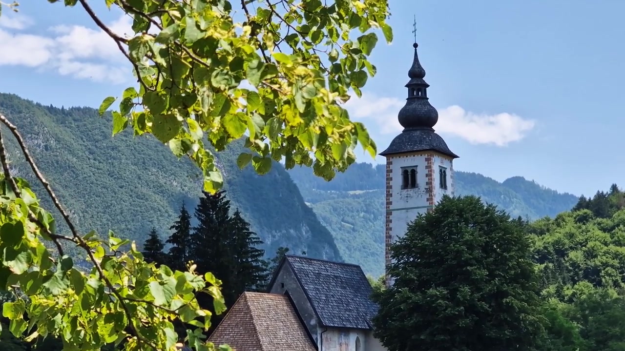Chiesa cattolica e paesaggio idilliaco delle Alpi in una soleggiata giornata estiva.