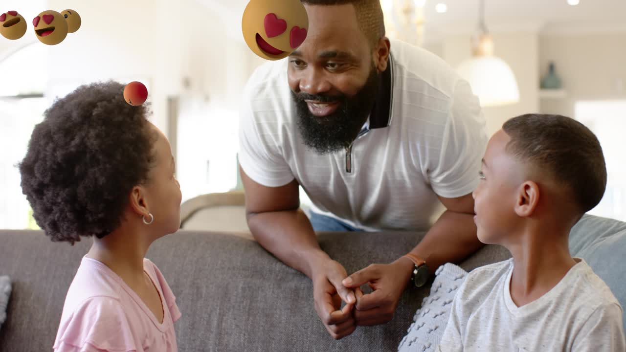 Bambini che applaudono su un divano grigio con sovrapposizione di emoji scintillanti mentre il padre fa il gesto del pugno per rinsaldare i legami familiari