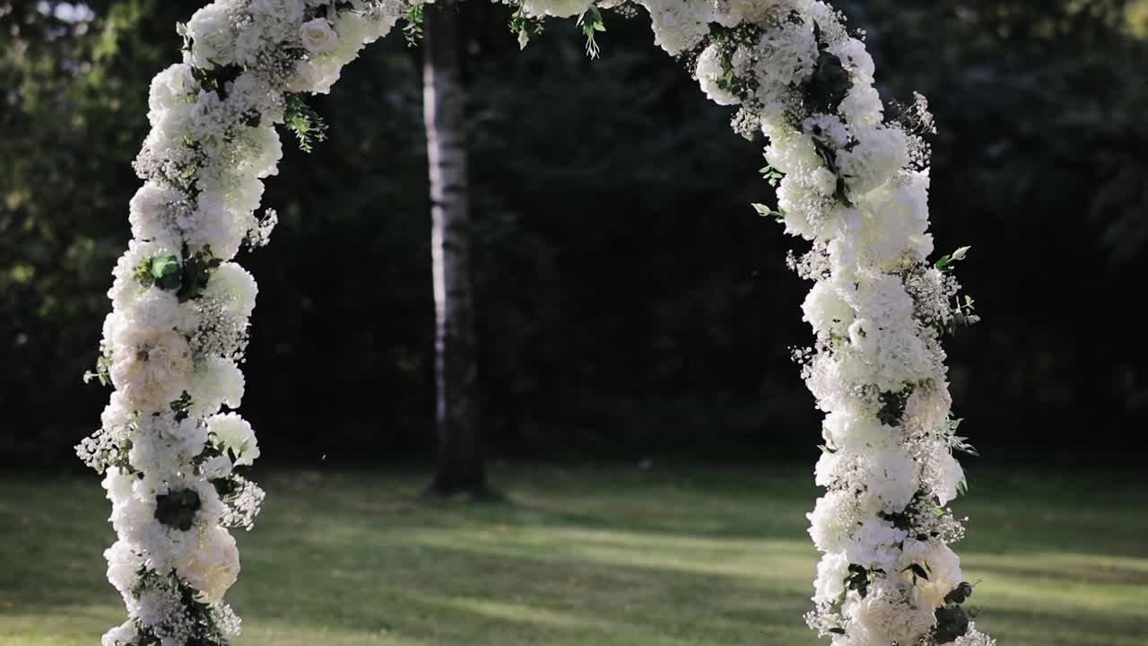 Decorazioni floreali nuziali, arco di fiori in giardino, cerimonia di matrimonio all'aperto nel parco, i raggi del sole splendono attraverso l'arco.
