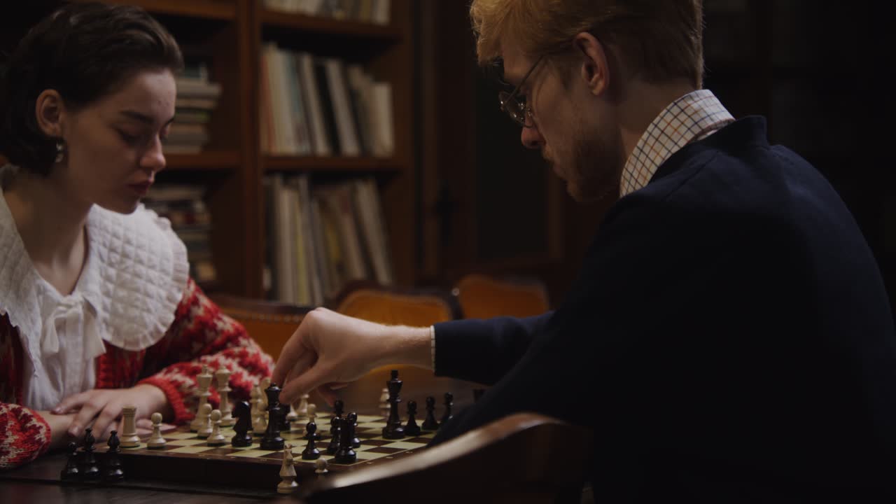 пара играет в шахматы в библиотеке