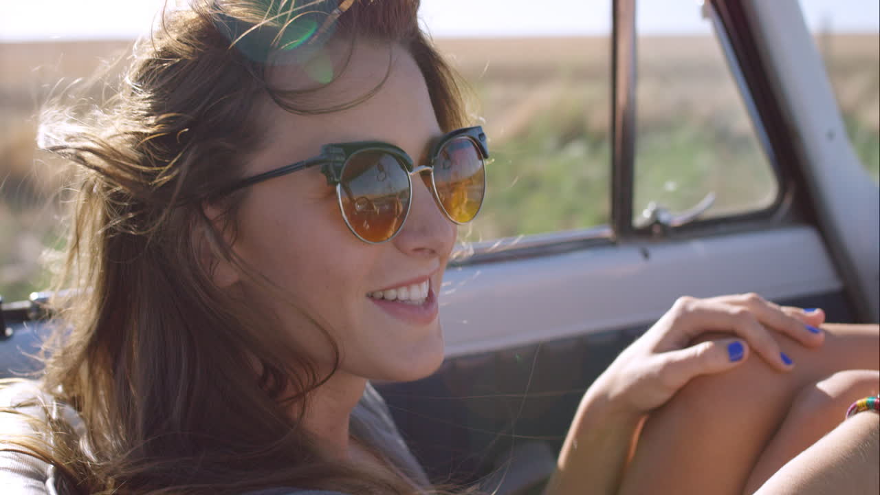 beautiful girl on adventure road trip in vintage convertible enjoying the wind in her hair