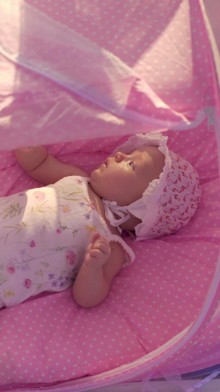 Neonato in una culla rosa in spiaggia