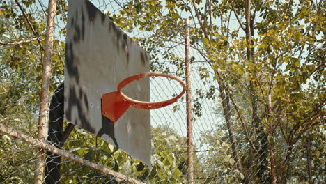 orange ball going through the round hoop basket with steel backboard of basketball in slowmo