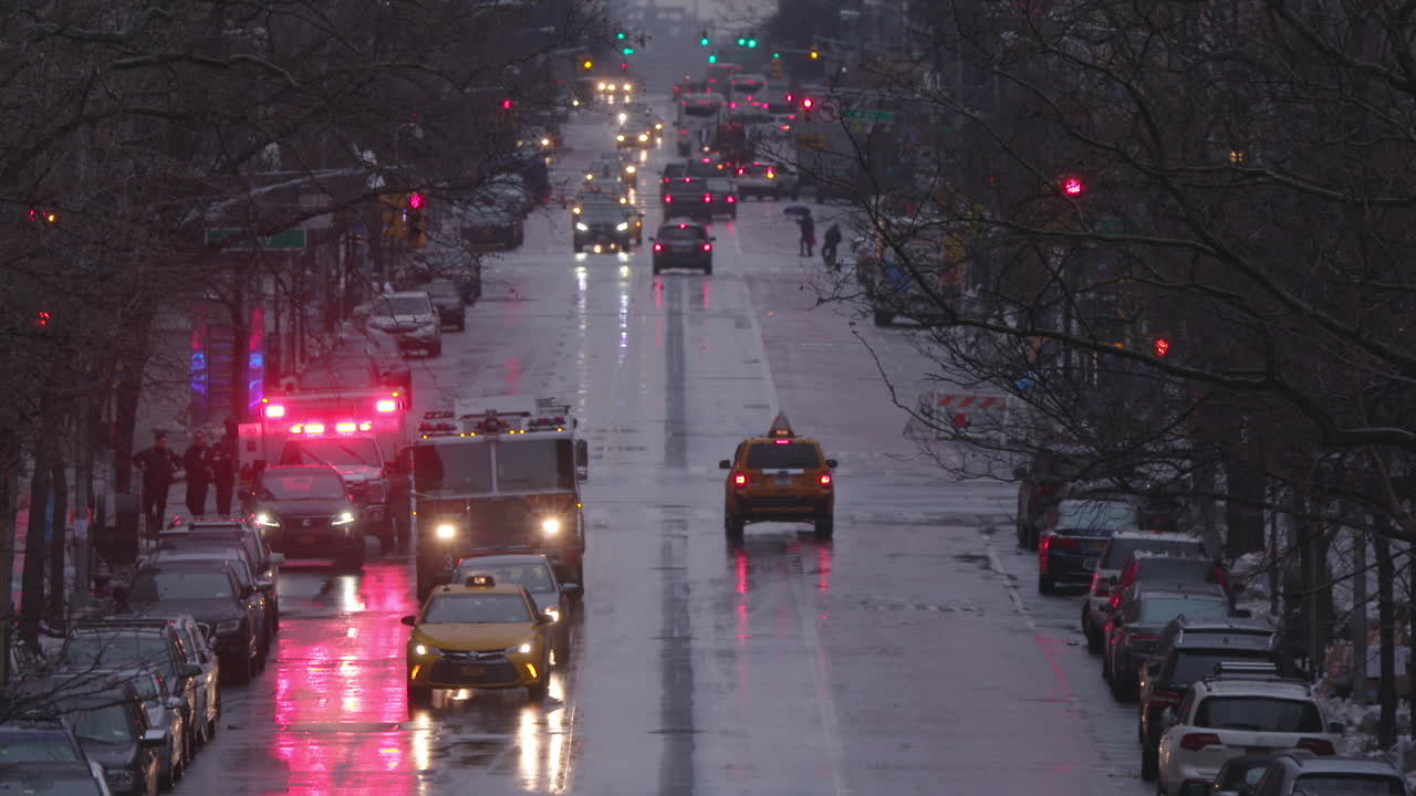 cámara lenta del tráfico de nueva york con camión de bomberos y ambulancia en una calle principal mojada de manhattan