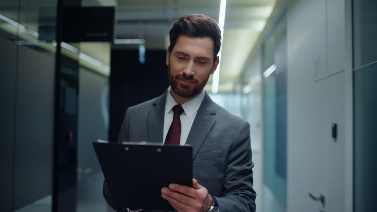 Bearded boss reviewing contracts on go walking contemporary office hall closeup