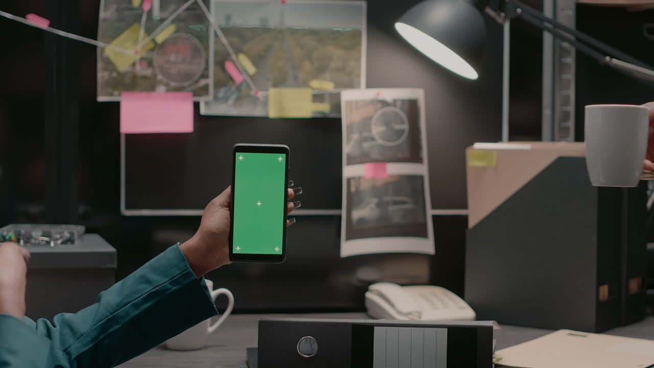 Images featuring a smartphone with green screen on a detective's desk