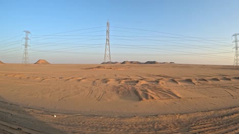 Dunas-Del-Desierto-Con-Pirámides-En-El-Fondo-Detrás-De-Pilones-En-Un-Paisaje-Arenoso-Y-Polvoriento