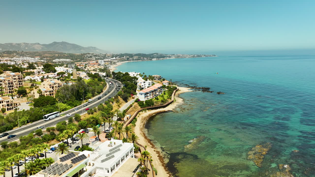 vista aérea de la carretera costera, los edificios, el mar turquesa y el cielo azul claro en mijas, españa, en un día soleado