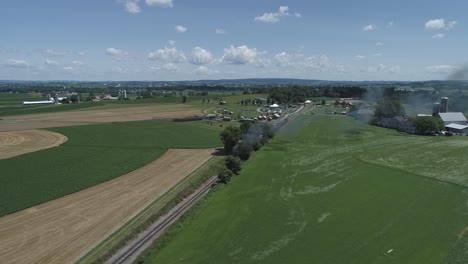 vista aérea de las tierras de cultivo y el campo con un tren de vapor antiguo que resopla en un día soleado de verano