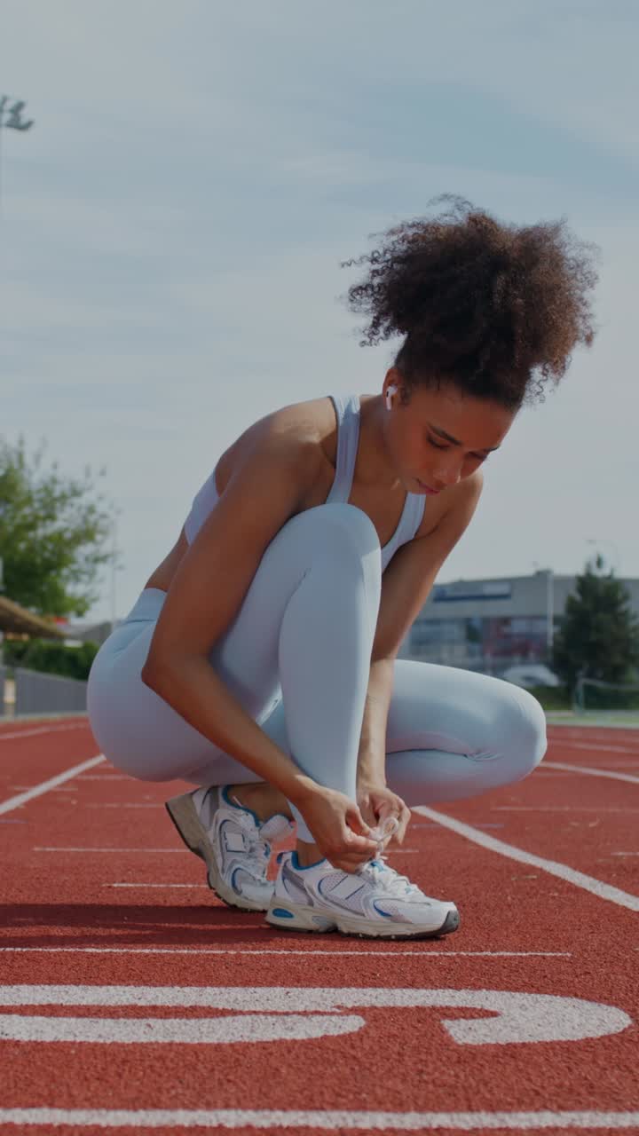 Donna che si allaccia le scarpe su pista di atletica
