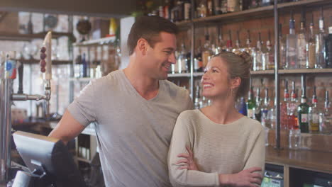 Portrait-Of-Smiling-Couple-Owning-Bar-Standing-Behind-Counter